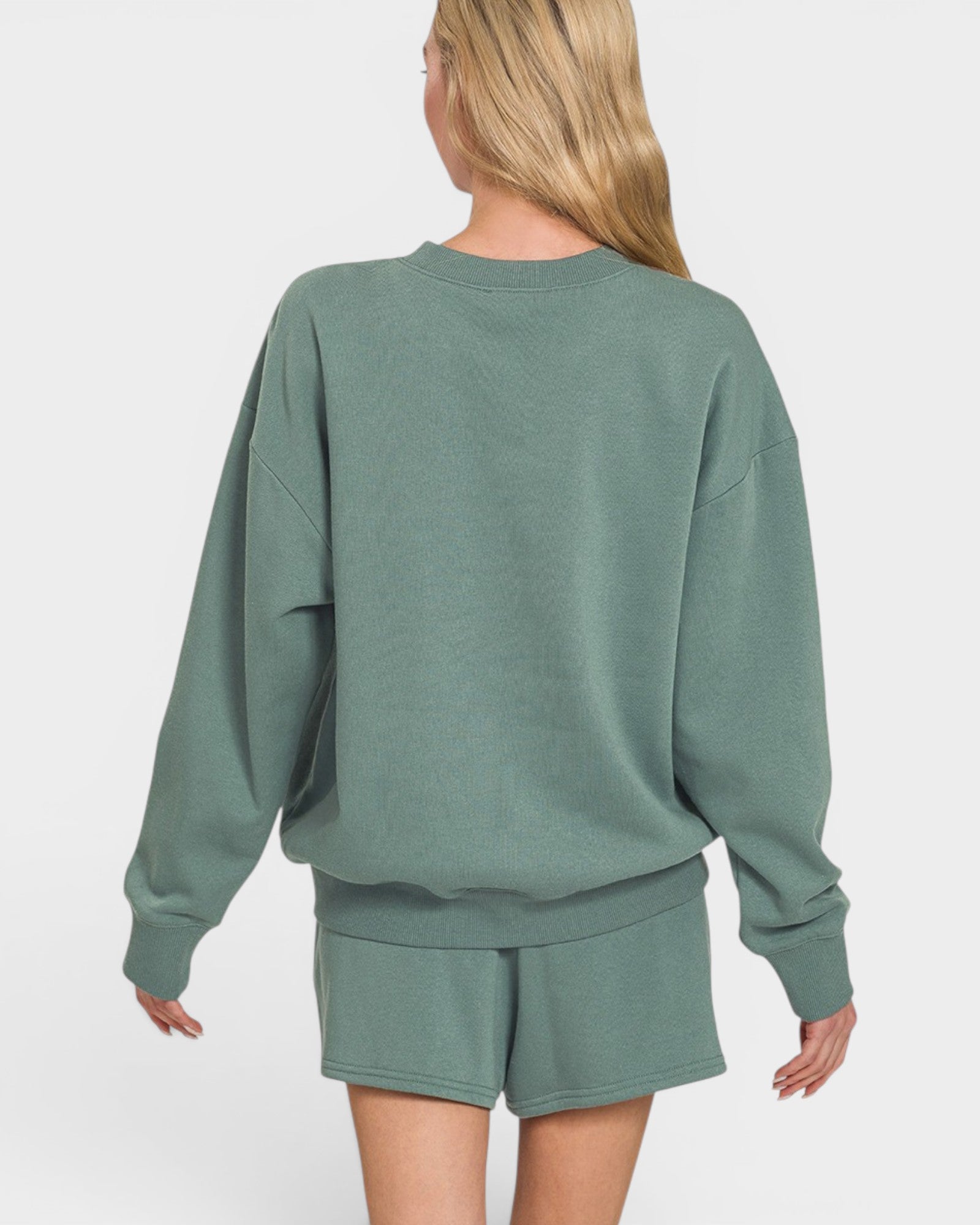 Person wearing a green sweatshirt and shorts set on a white background