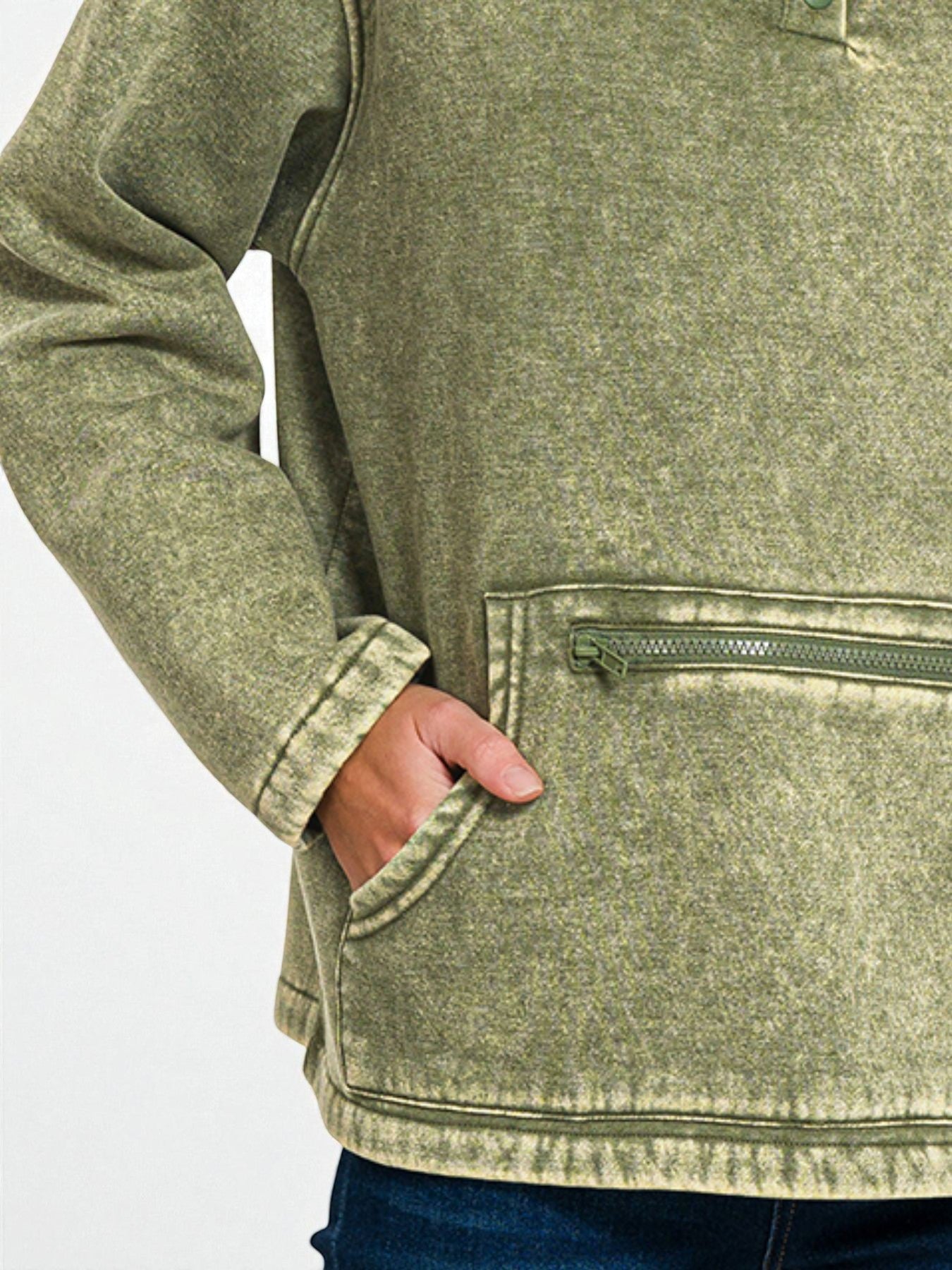 Close-up of a person wearing a green fleece jacket with a pocket on a white background