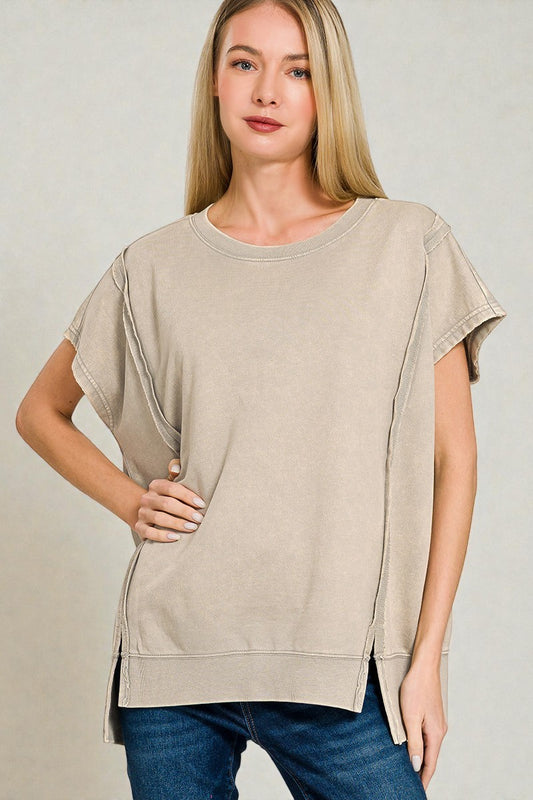Woman wearing a beige oversized t-shirt against a plain background