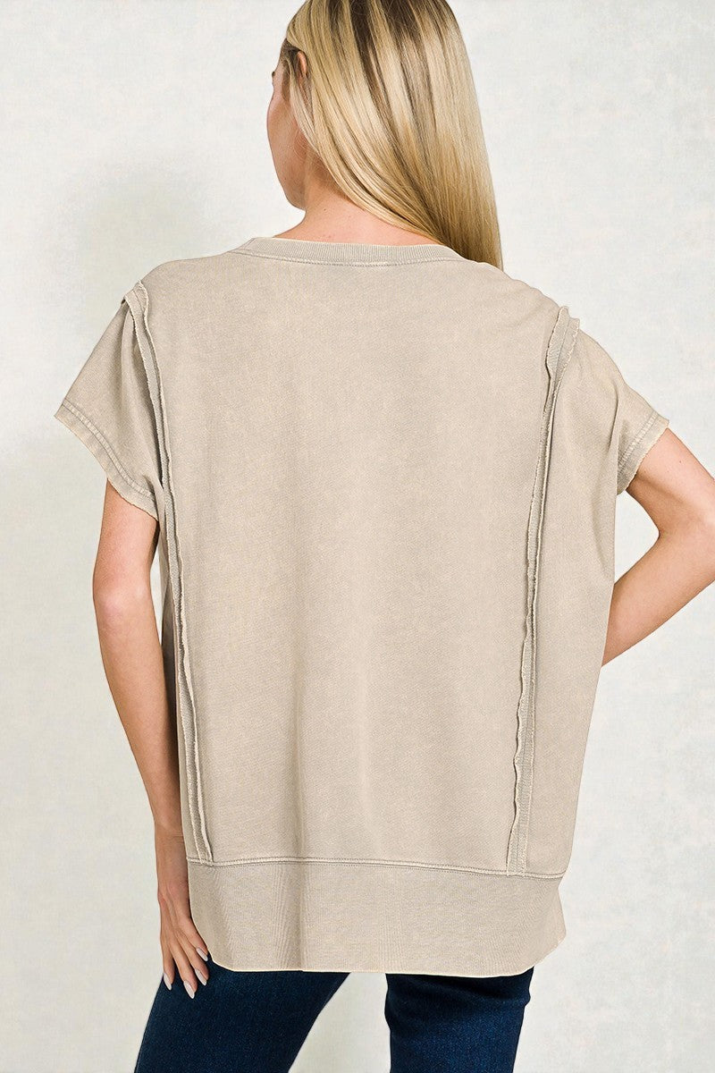 Woman wearing a beige tunic with short sleeves against a plain background