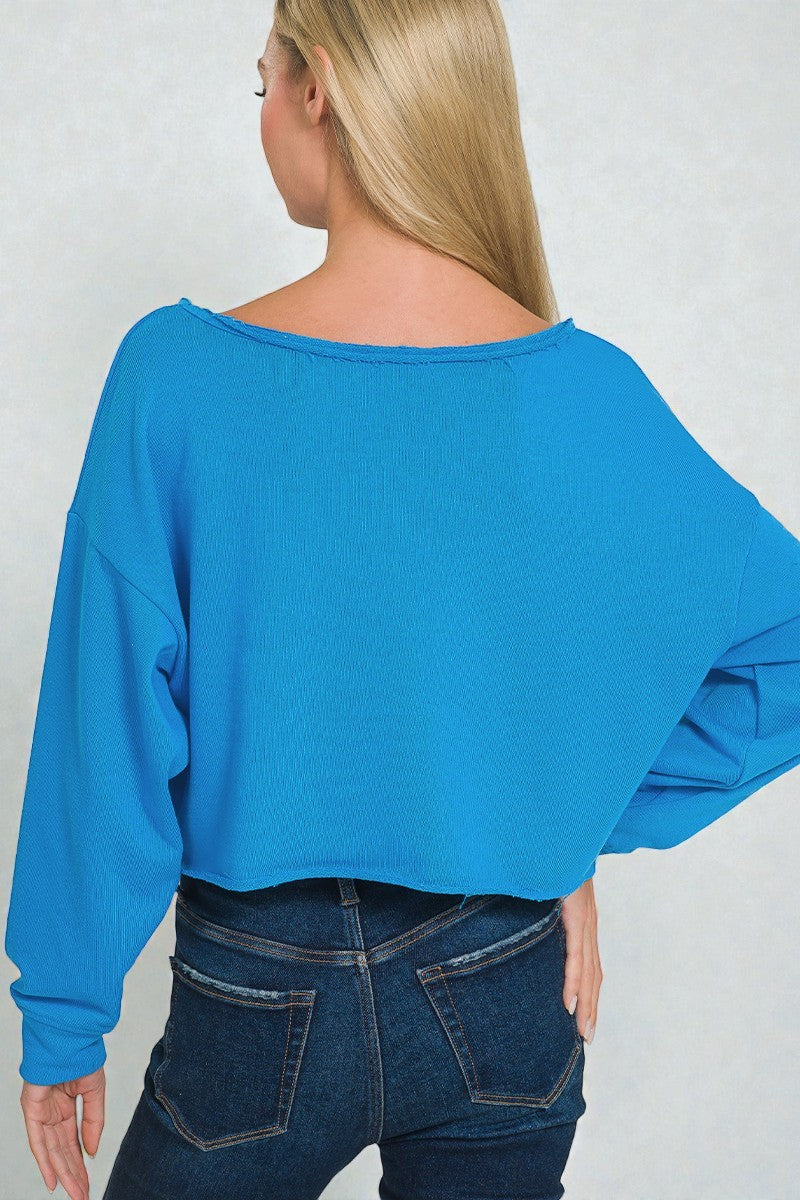Person wearing a blue sweater and dark jeans against a plain background