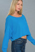 Woman wearing a blue long-sleeve top against a gray background