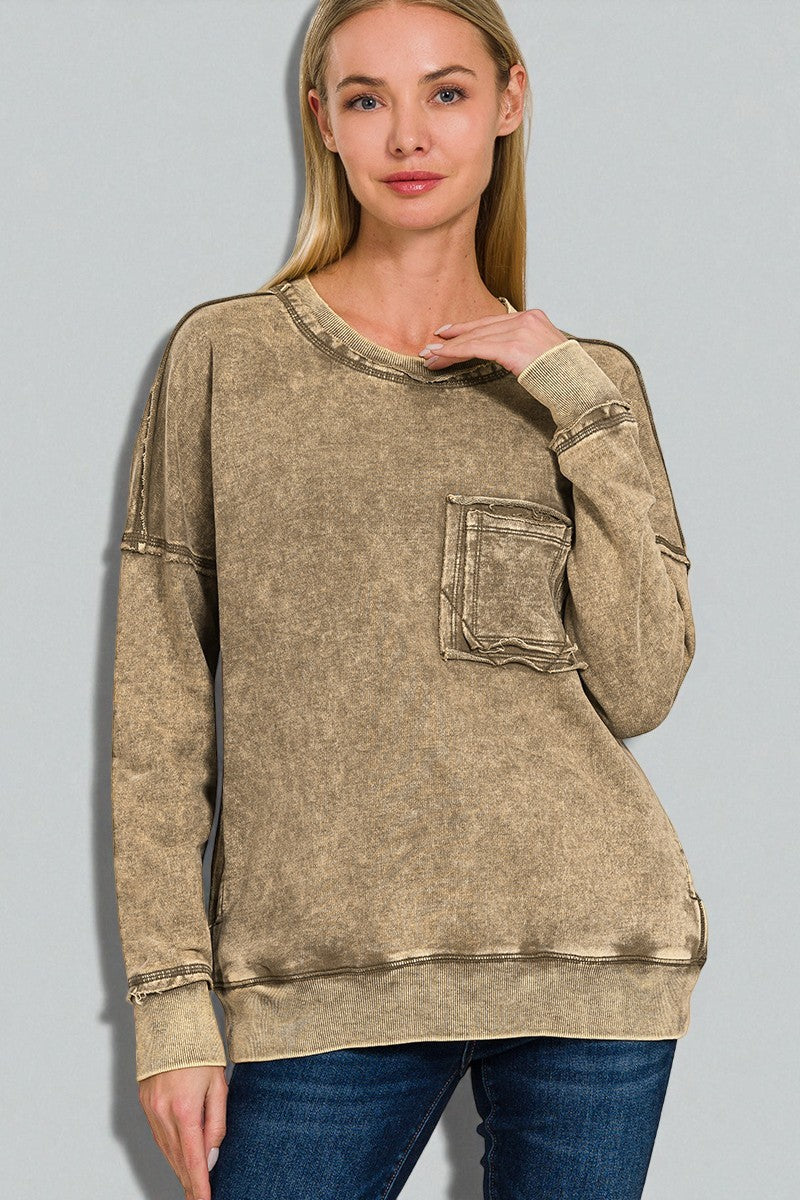Woman wearing a beige distressed sweatshirt against a gray background