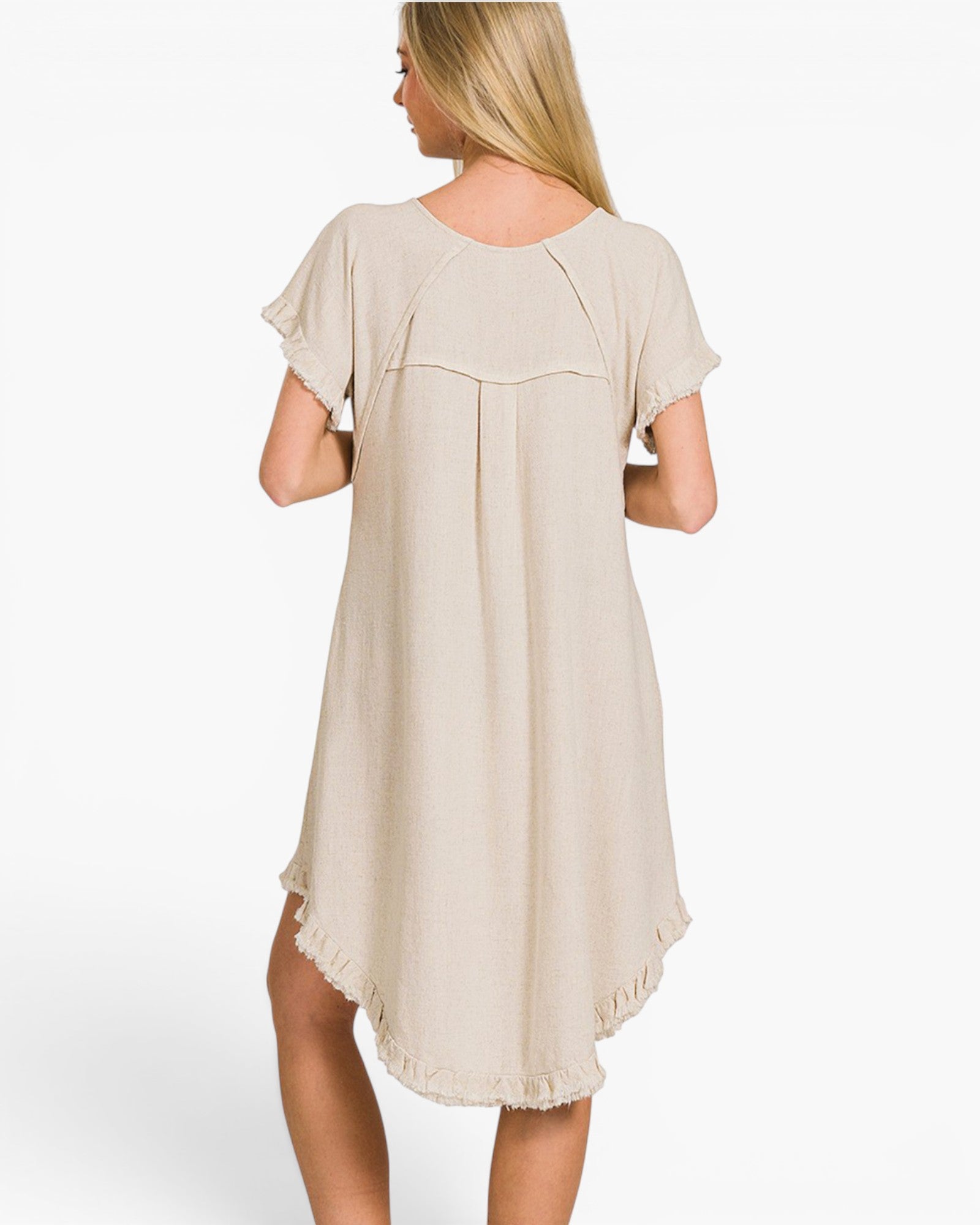 A woman shown from the back wearing a light beige short-sleeve dress with a ruffled hem, photographed against a plain white studio background.