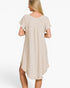 A woman shown from the back wearing a light beige short-sleeve dress with a ruffled hem, photographed against a plain white studio background.
