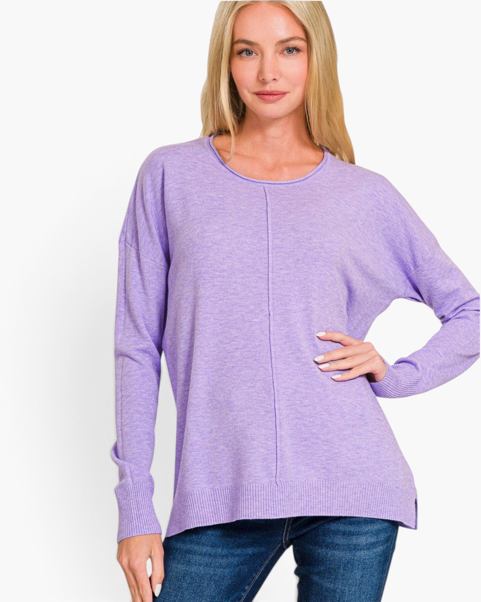 A woman modeling a lavender heather long-sleeve knit top with a crew neck and a central seam detail, paired with blue jeans against a plain white background.