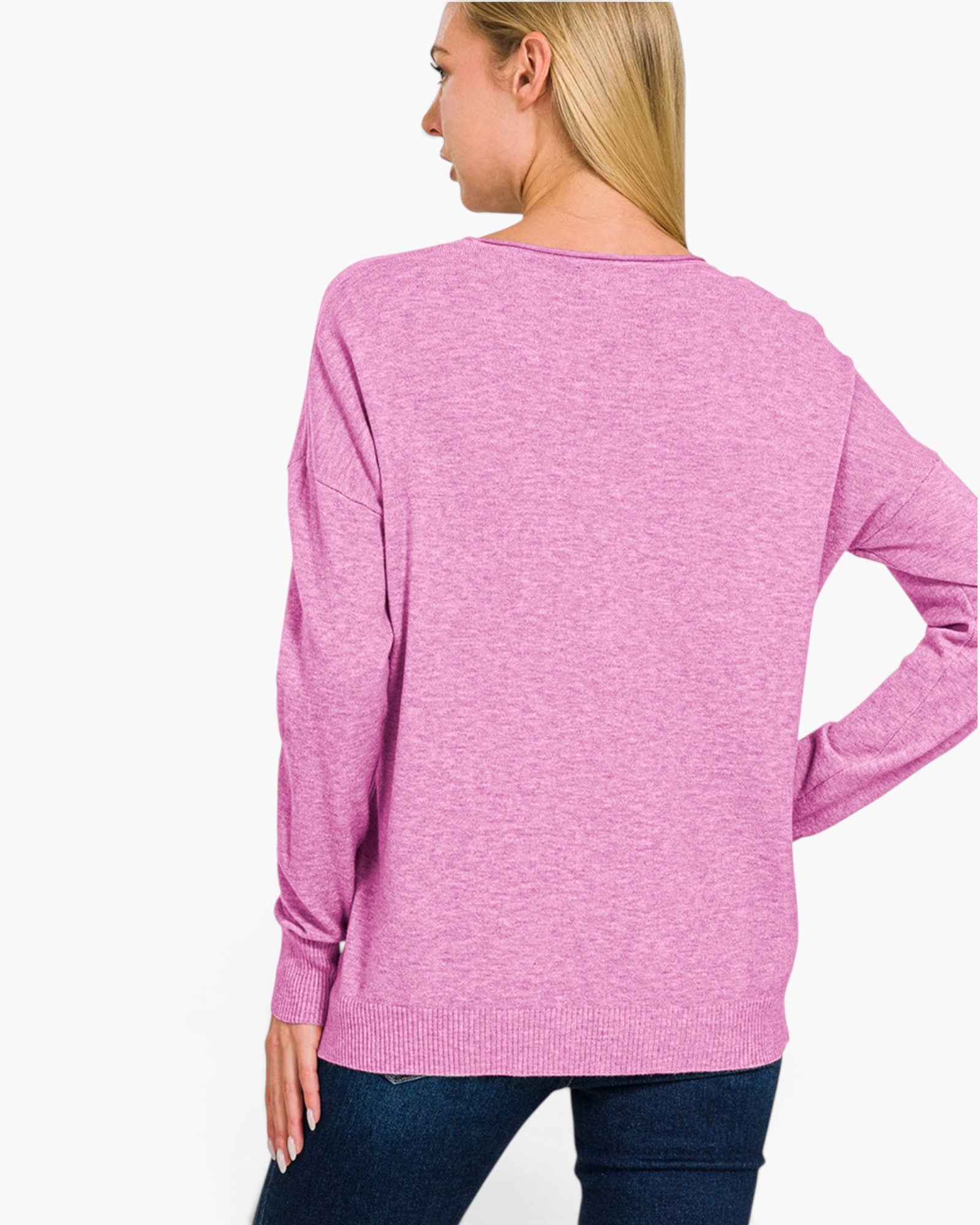 A woman shown from the back wearing a heather pink long-sleeve knit top and dark blue jeans against a plain white background.