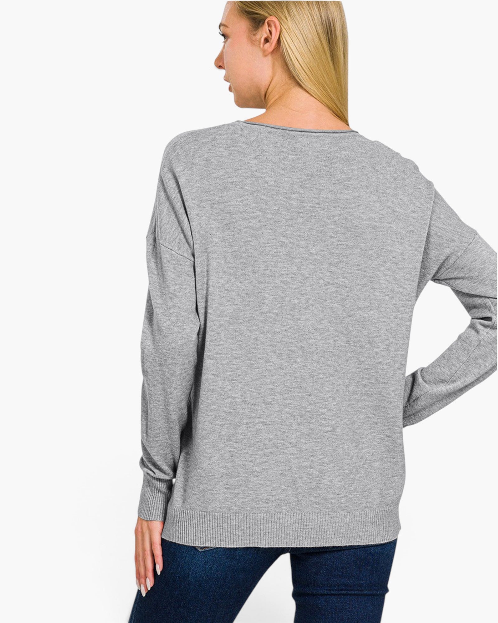 A woman shown from the back wearing a heather gray long-sleeve knit top and dark blue jeans against a plain white studio background.