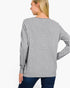 A woman shown from the back wearing a heather gray long-sleeve knit top and dark blue jeans against a plain white studio background.
