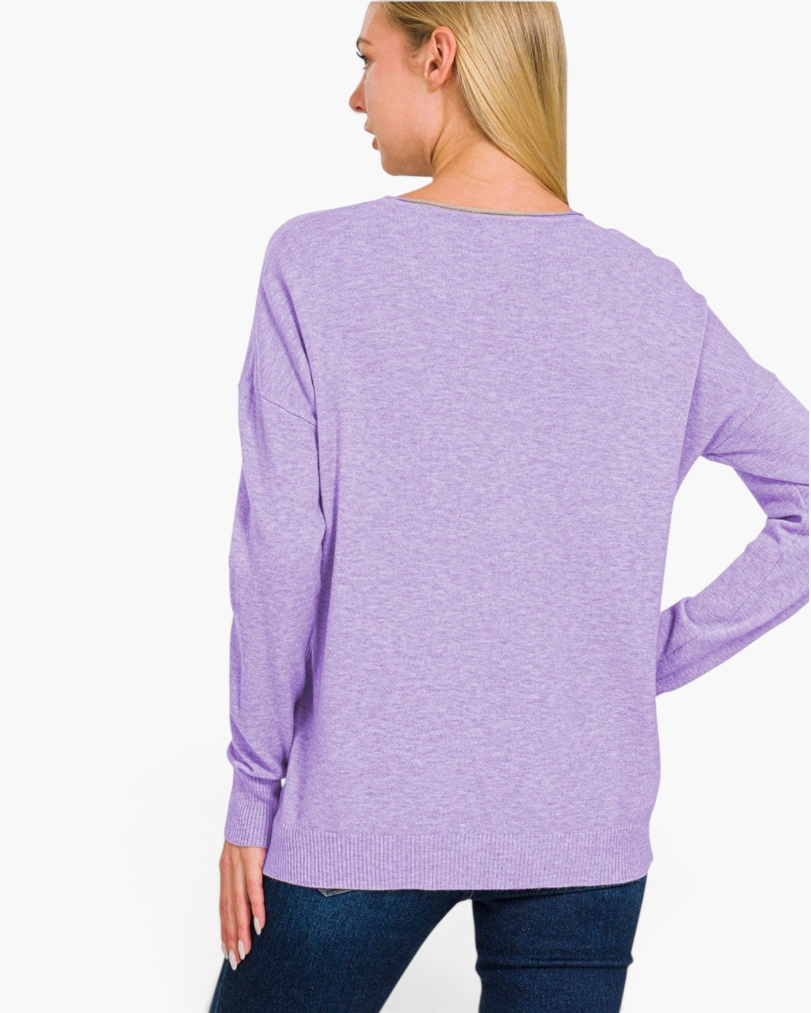 A woman shown from the back wearing a lavender heather long-sleeve knit top and dark blue jeans against a plain white background.