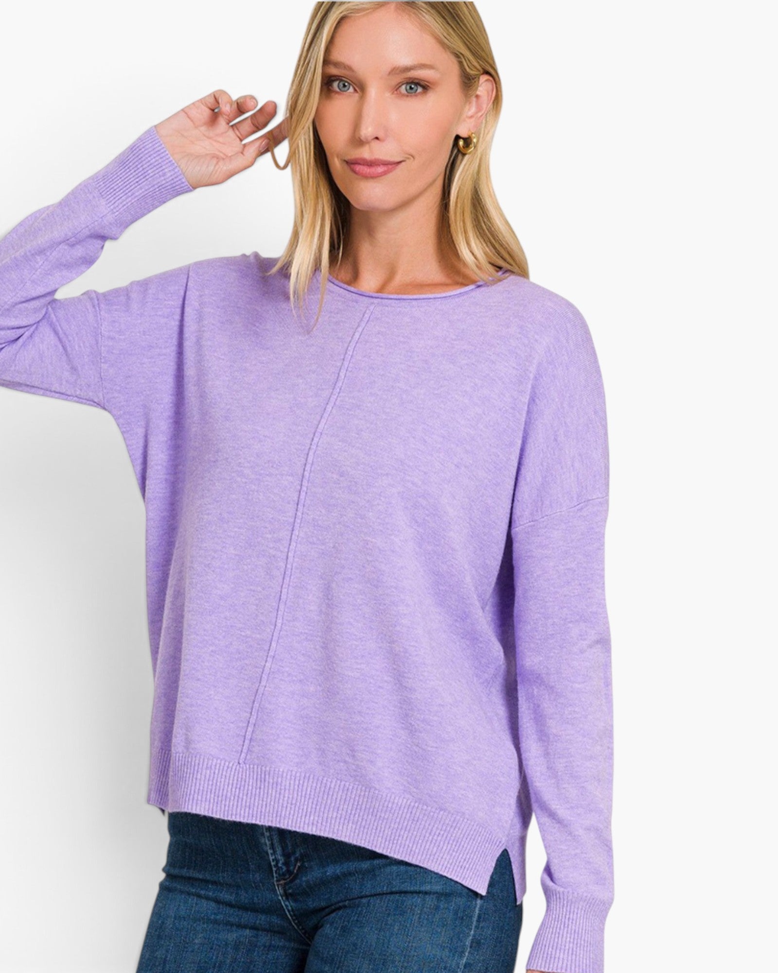 A woman wearing a light purple knit sweater with a crew neck and drop shoulders, paired with blue jeans, against a plain white background.