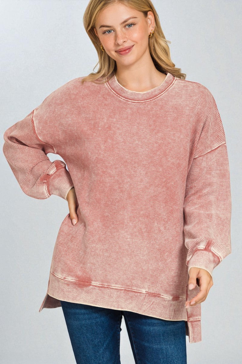 Woman wearing a pink distressed sweatshirt against a plain background