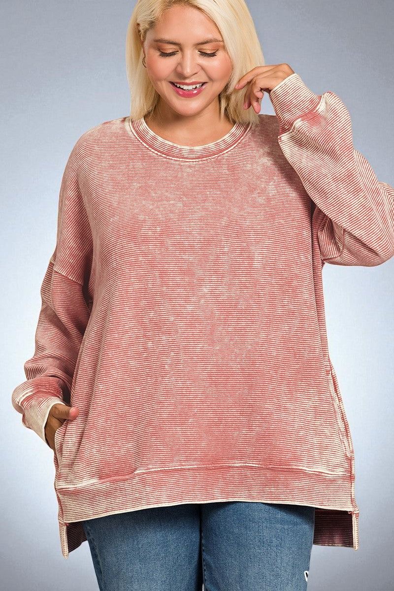 Woman wearing a pink distressed sweatshirt against a plain background