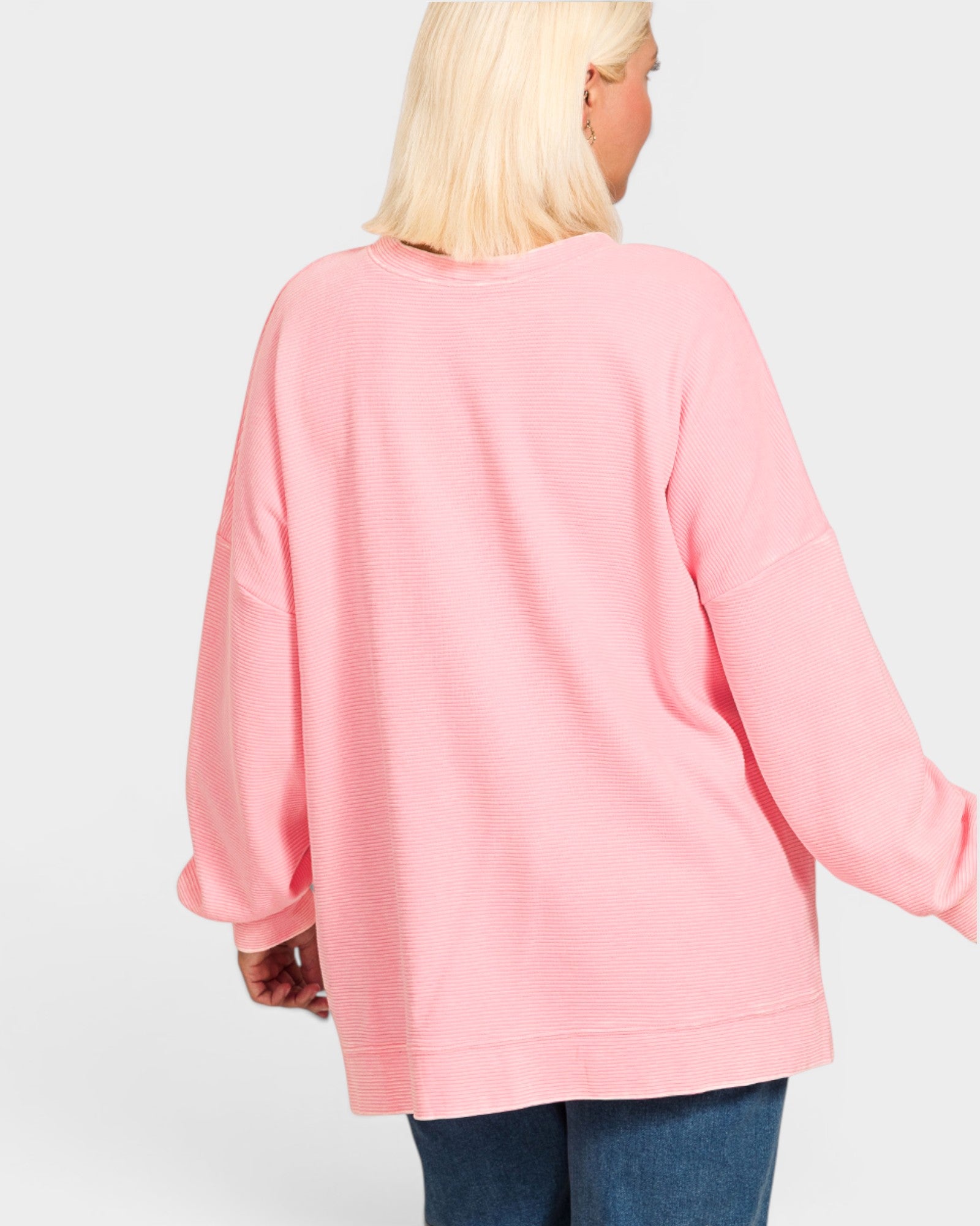 Person wearing a pink sweater on a plain background