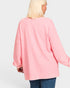Person wearing a pink sweater on a plain background