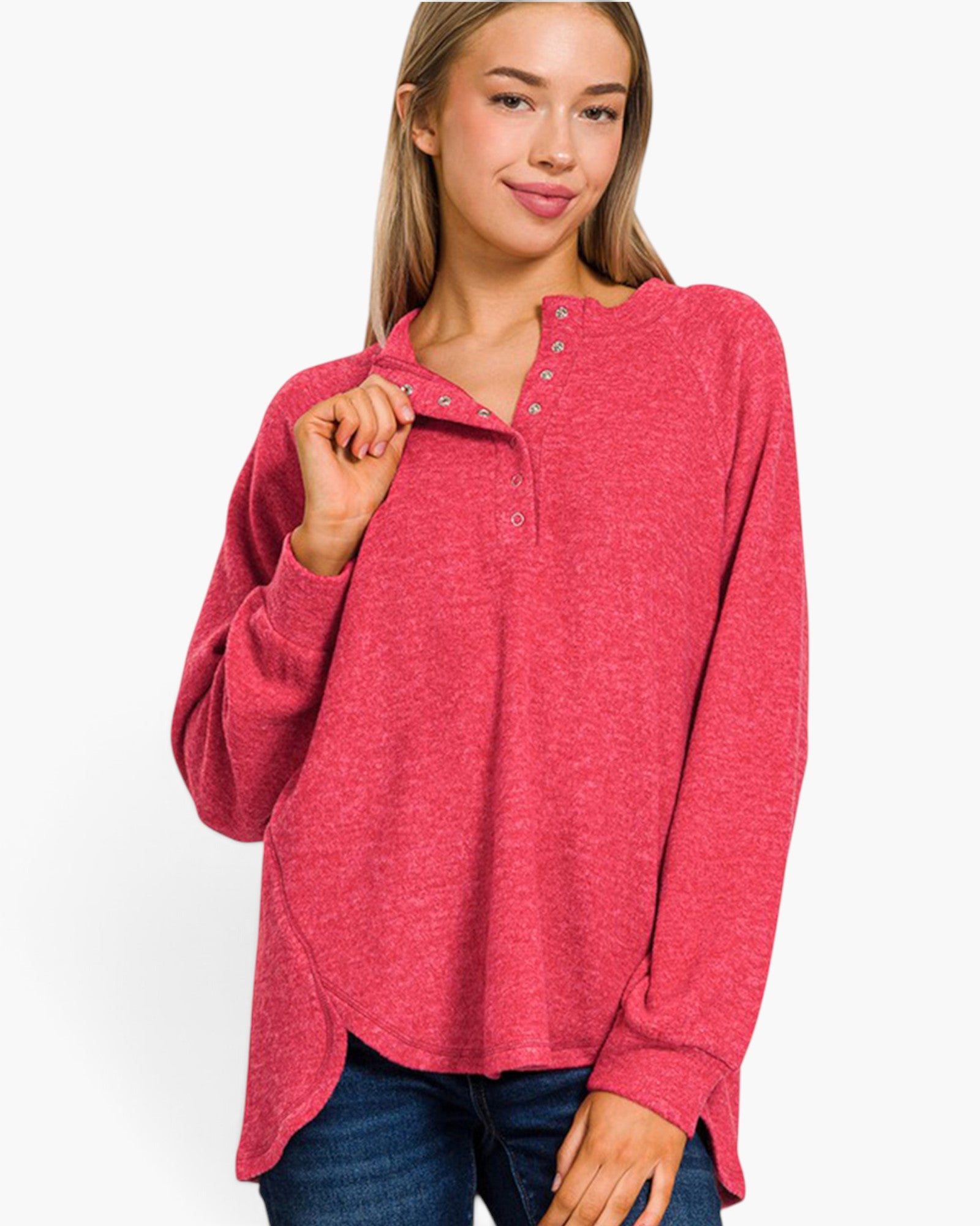 A woman wearing a heathered pink long-sleeve henley top with a buttoned collar, paired with blue jeans, against a plain white background.
