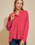 Woman wearing a red long-sleeve shirt against a beige background