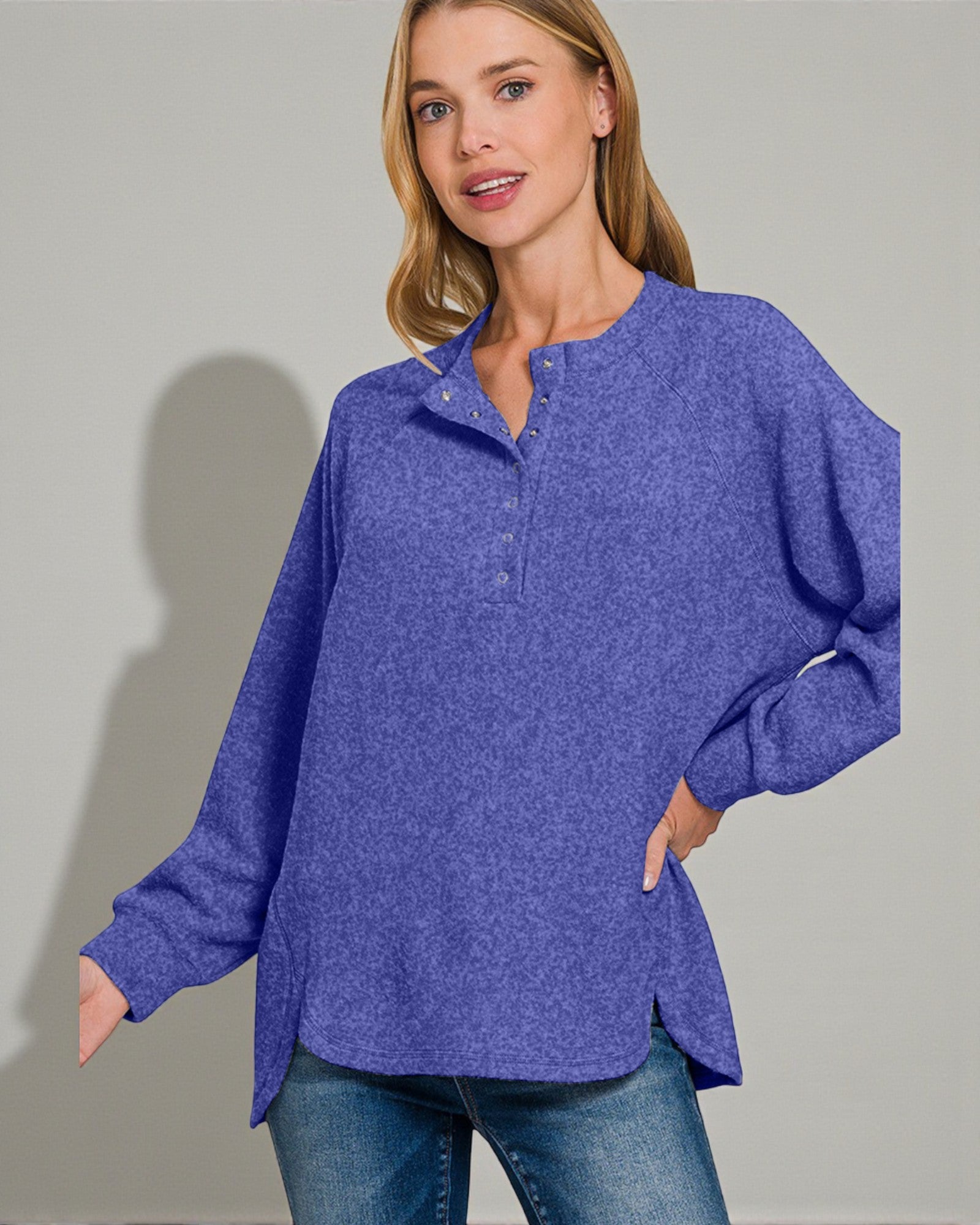 Woman wearing a blue long-sleeve shirt against a gray background