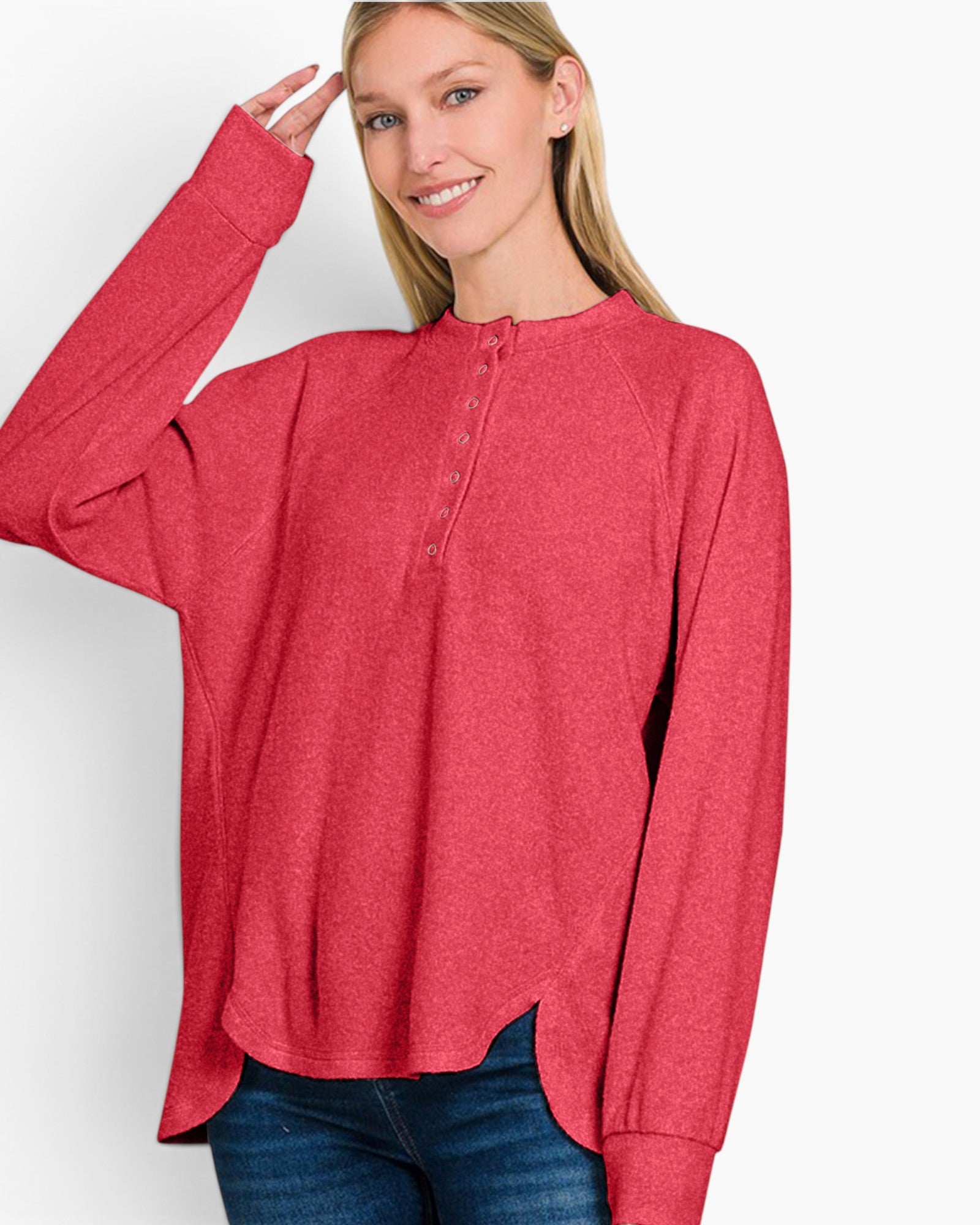 A woman wearing a heathered red long-sleeve henley top with a button placket, paired with blue jeans, against a plain white studio background.