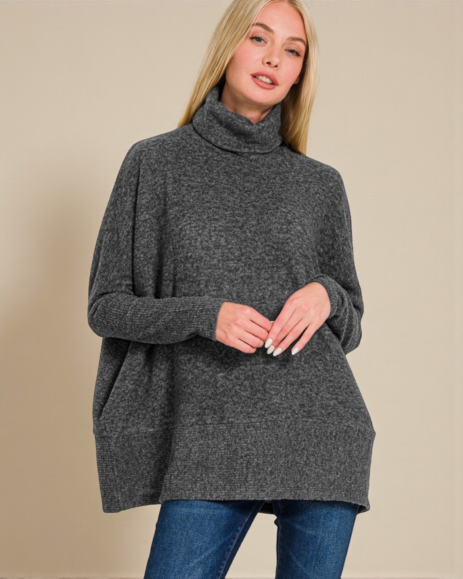 Woman wearing a gray turtleneck sweater against a beige background