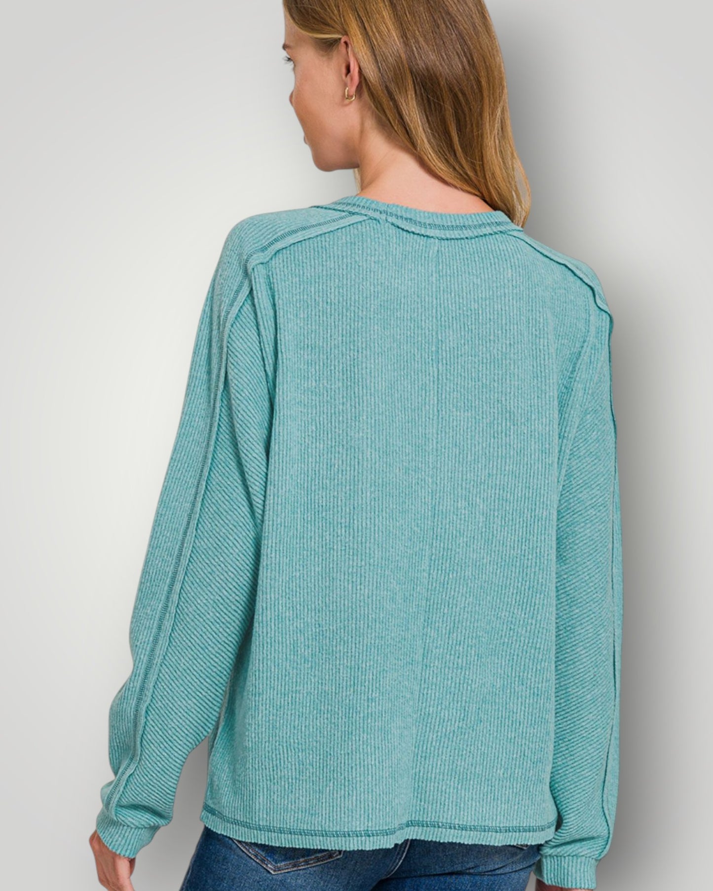 Person wearing a teal long-sleeve shirt against a plain background