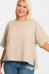 Woman wearing a beige oversized sweater and blue jeans on a plain background