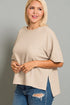 Woman wearing a beige sweater and blue jeans against a gray background