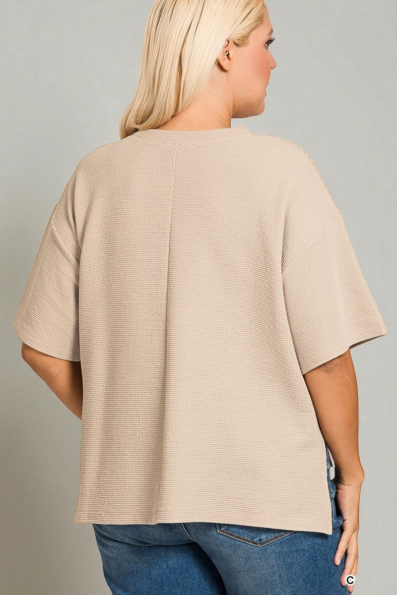 Person wearing a beige ribbed sweater and blue jeans on a gray background