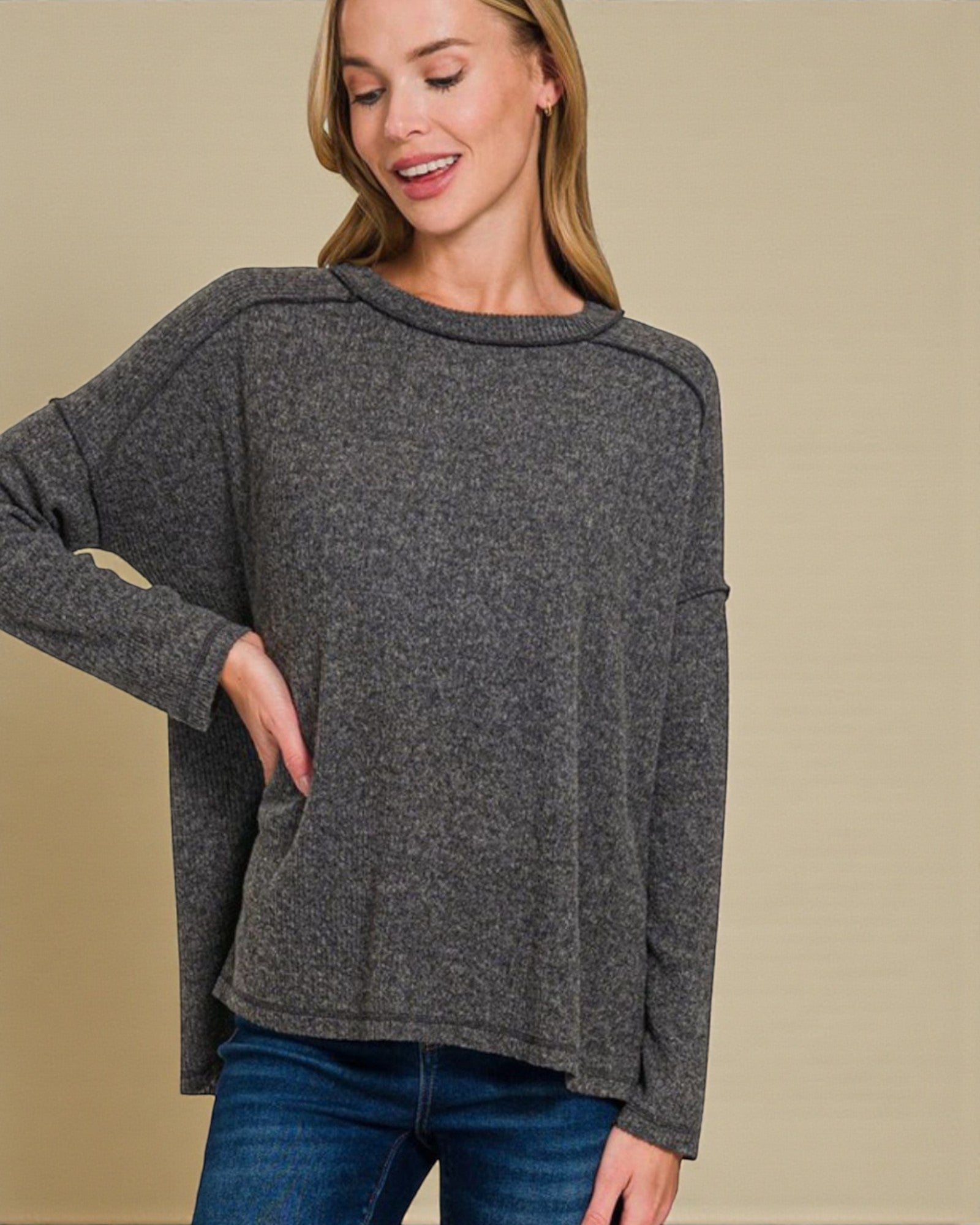 Woman wearing a gray sweater against a beige background