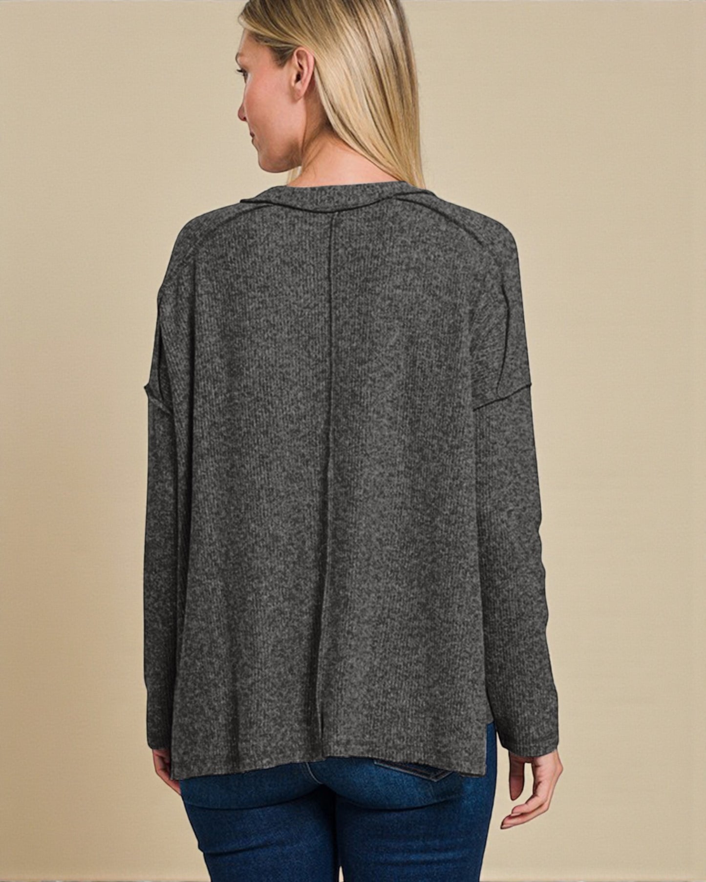 Person wearing a gray sweater with a beige background