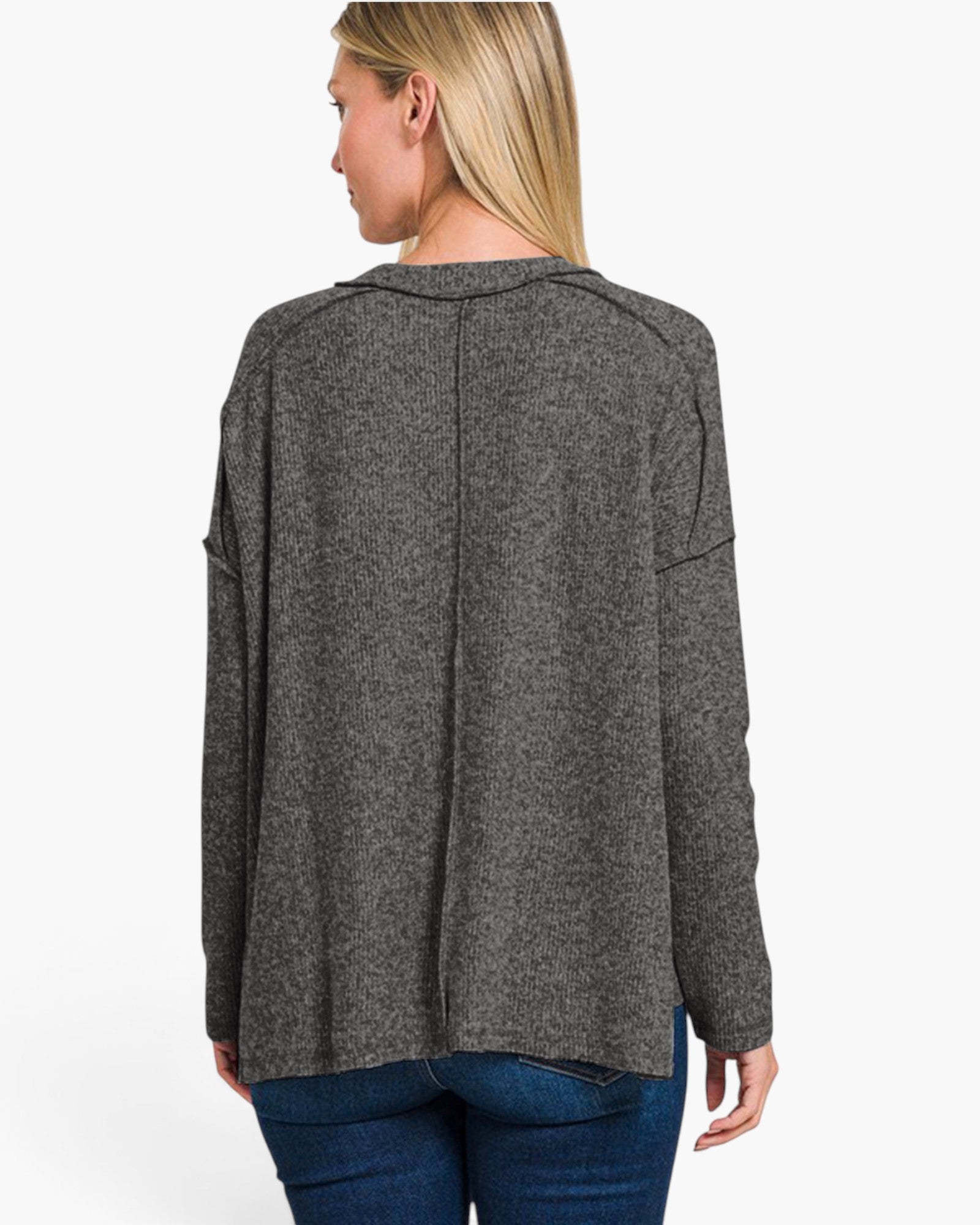A woman shown from the back wearing a dark gray heathered knit long-sleeve top and blue jeans against a plain white background.
