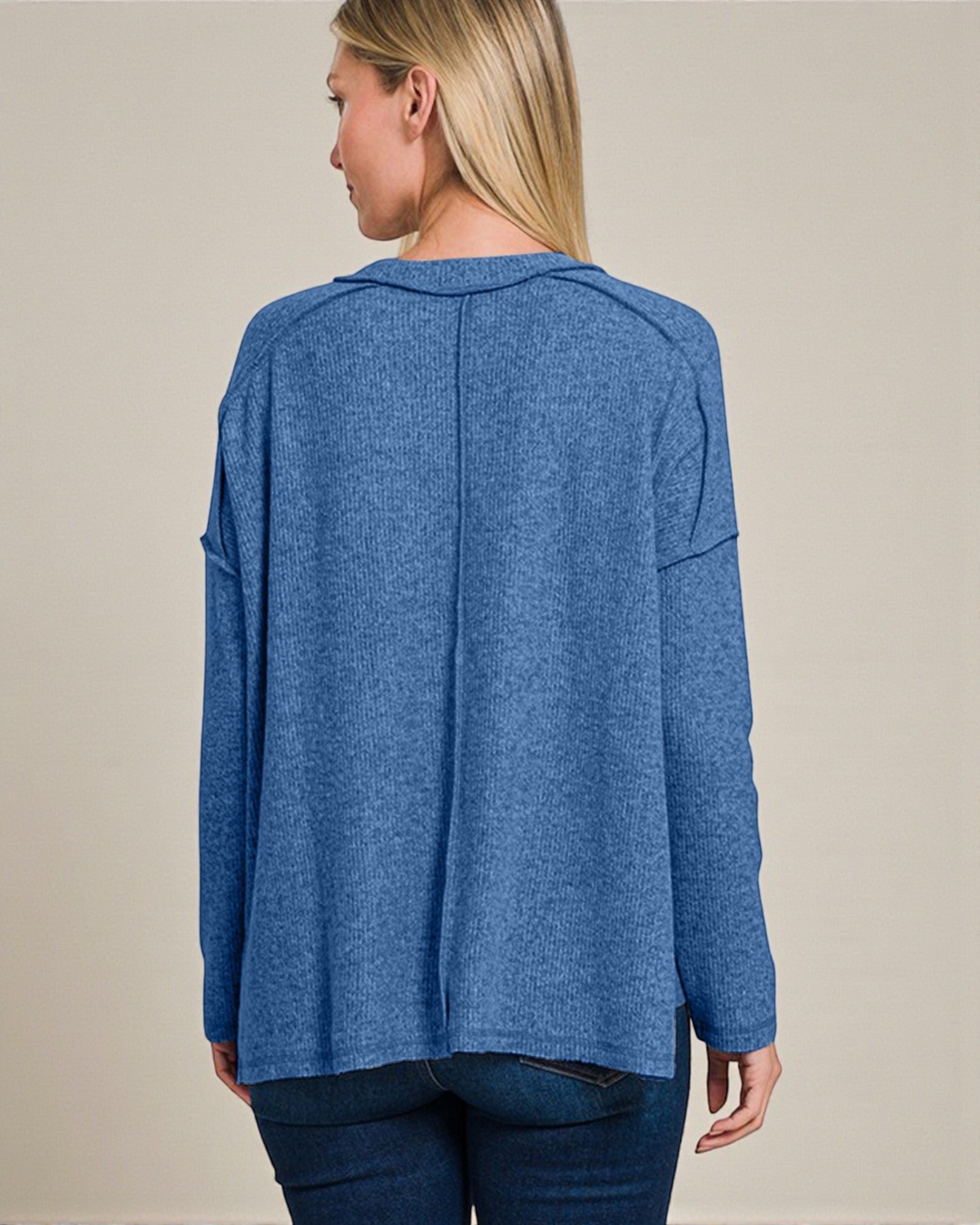 Woman wearing a blue sweater against a beige background