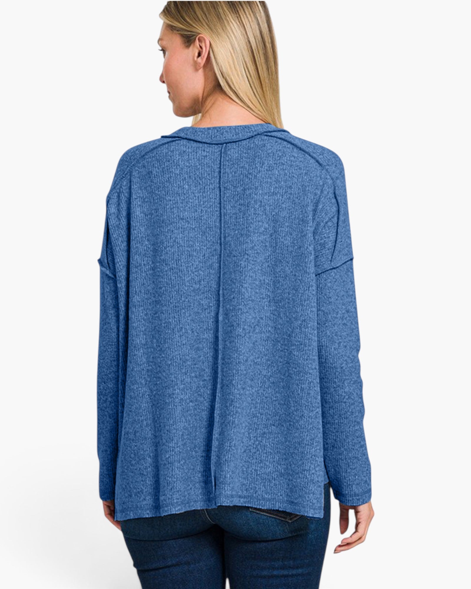 A woman shown from the back wearing a heathered blue long-sleeve top and dark blue jeans against a plain white studio background.