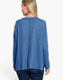 A woman shown from the back wearing a heathered blue long-sleeve top and dark blue jeans against a plain white studio background.