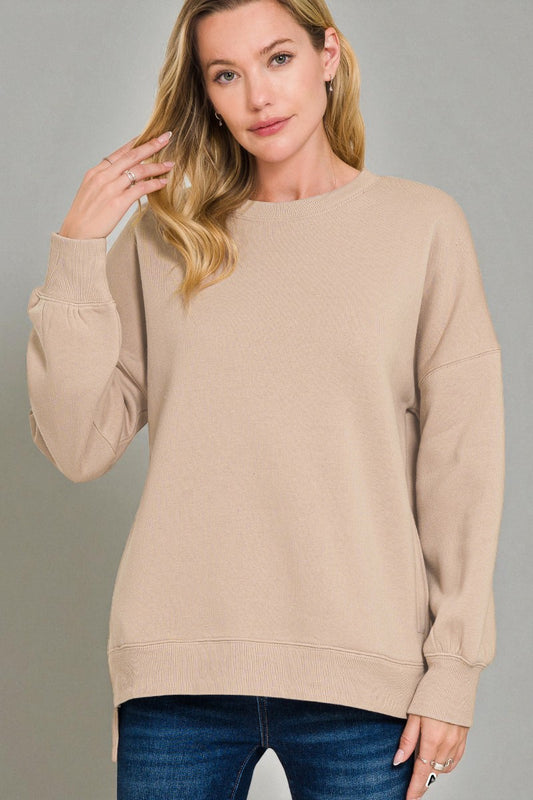 Woman wearing a beige sweater against a gray background