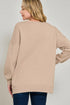 Woman wearing a beige sweater against a plain background