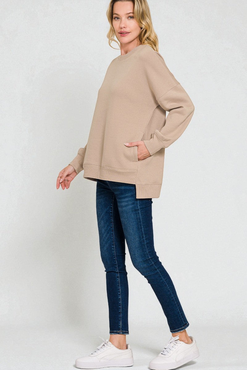 Woman wearing a beige sweater and blue jeans on a white background