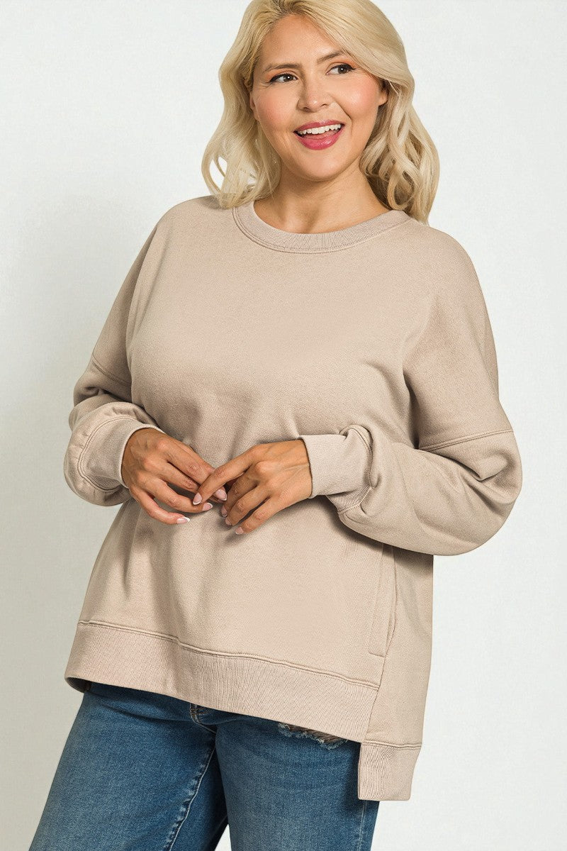 Woman wearing a beige sweater and blue jeans on a plain background