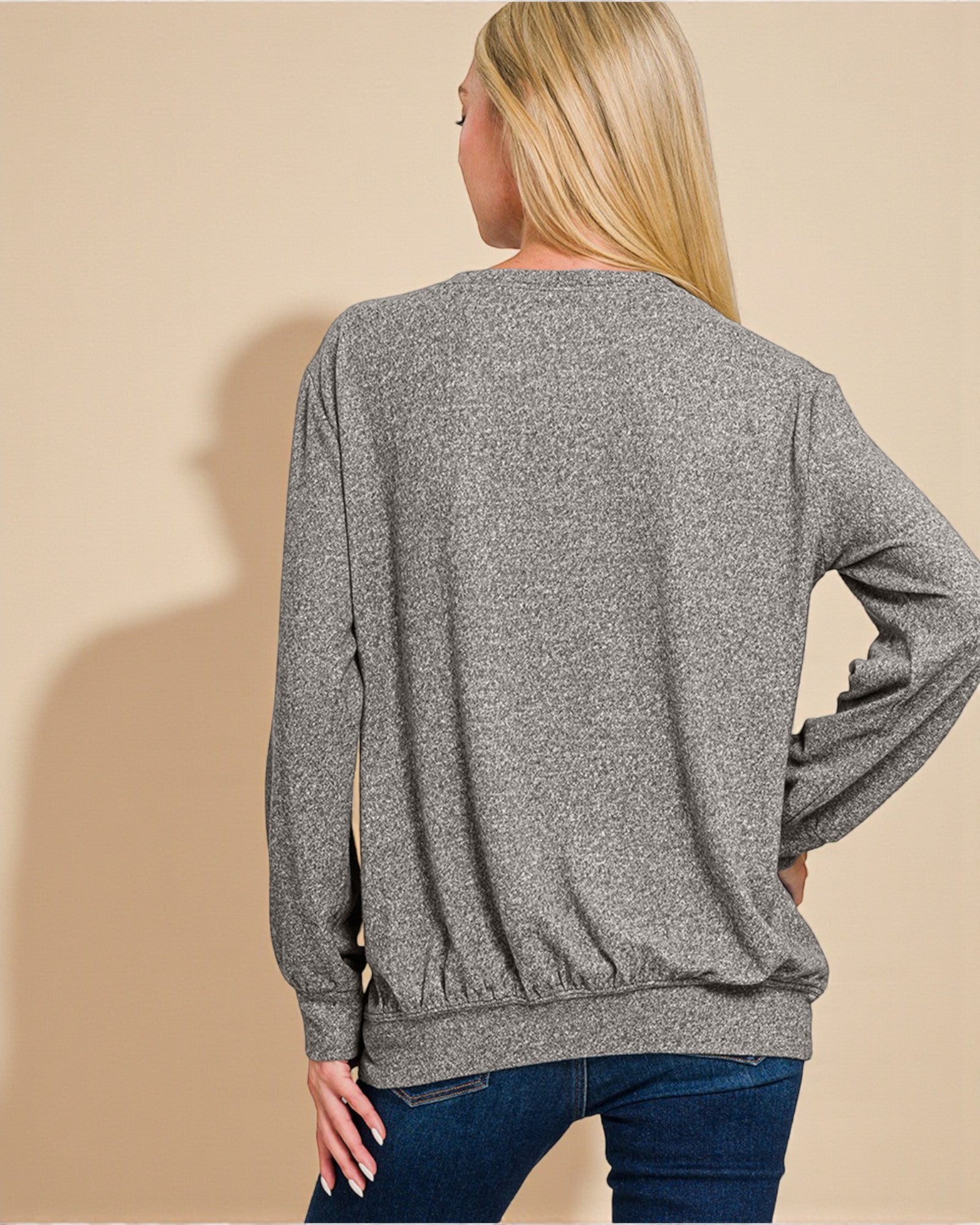 Person wearing a gray sweater against a beige background