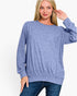 A woman wearing a heathered periwinkle blue long-sleeve crewneck sweater and dark blue jeans, posing against a solid white studio background.
