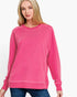 A woman wearing a bright pink crewneck sweatshirt with raglan sleeves, paired with blue jeans, against a plain white background.