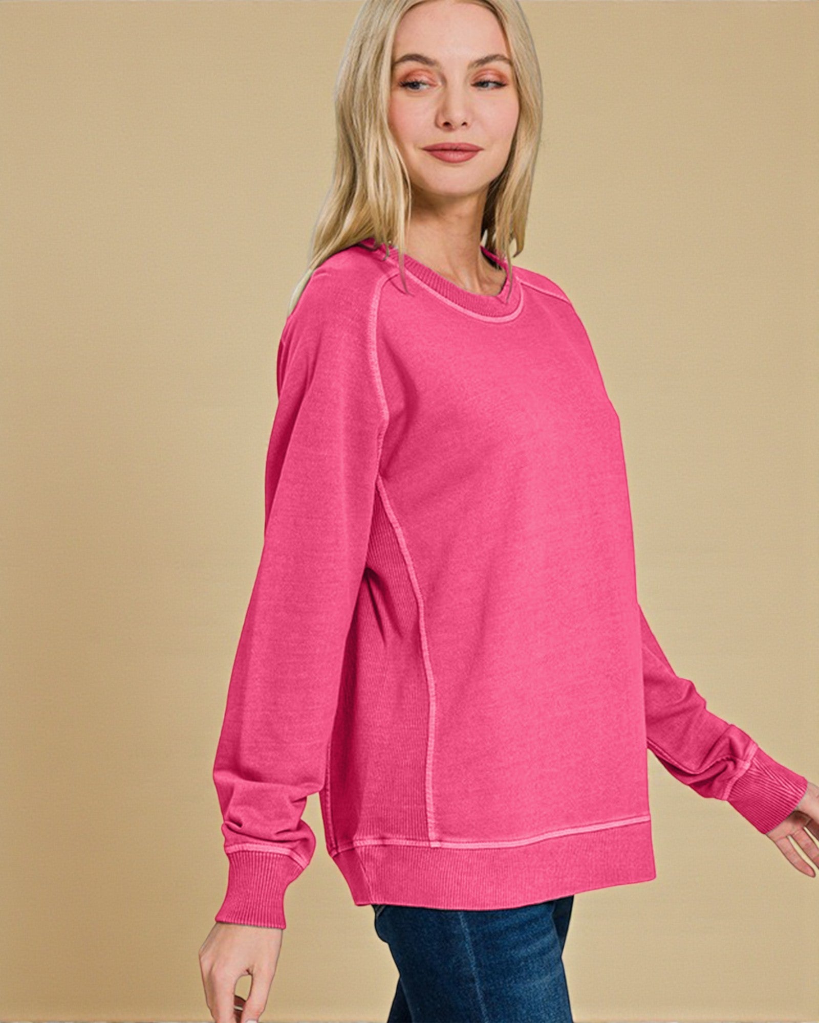 Woman wearing a pink sweatshirt against a beige background