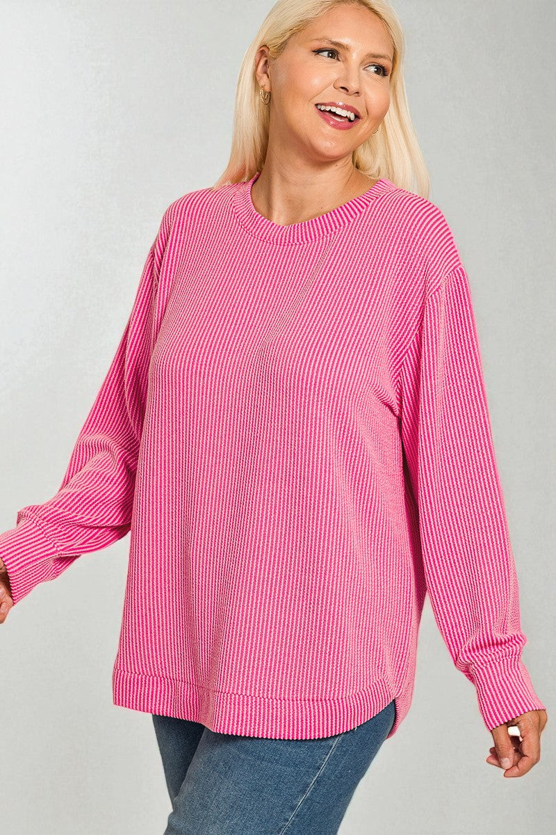 Woman wearing a pink ribbed sweater against a gray background