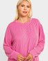 Woman wearing a pink ribbed sweater on a white background