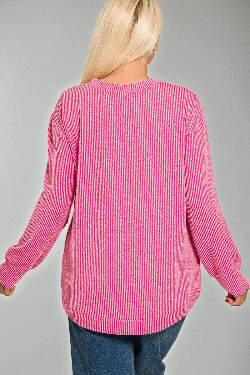 Person wearing a pink ribbed sweater on a gray background