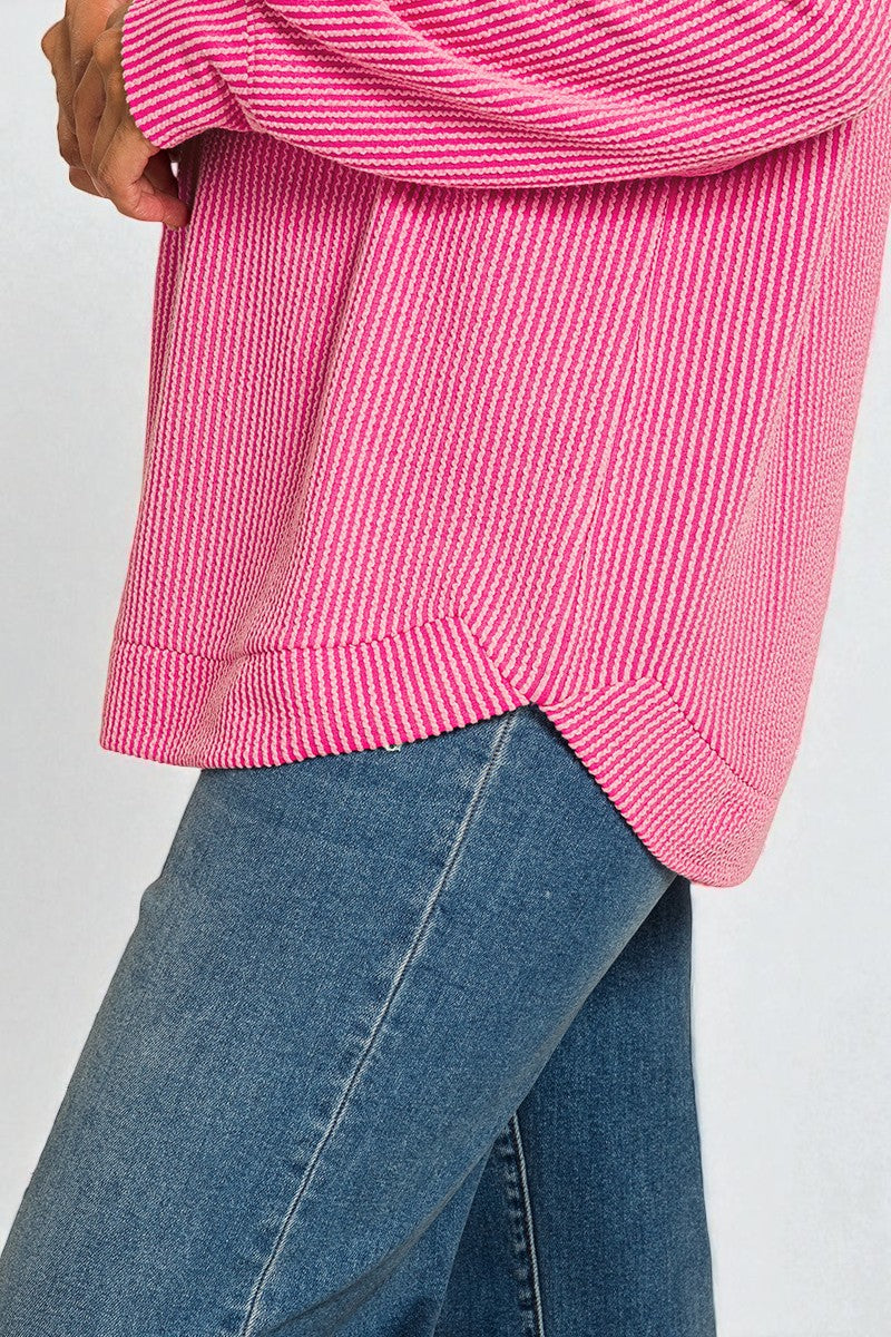 Close-up of a pink textured sweater and blue jeans against a white background