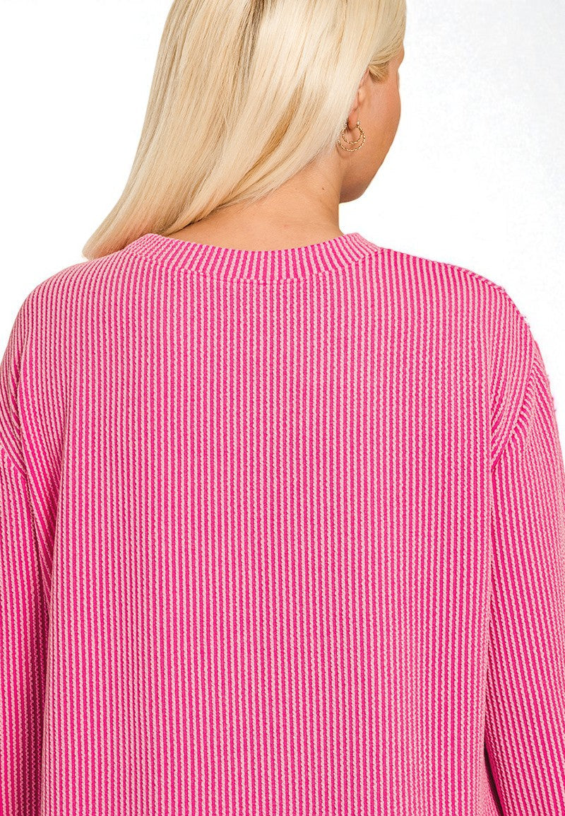 Close-up of a person wearing a pink ribbed sweater with 'Fuchsia' text.