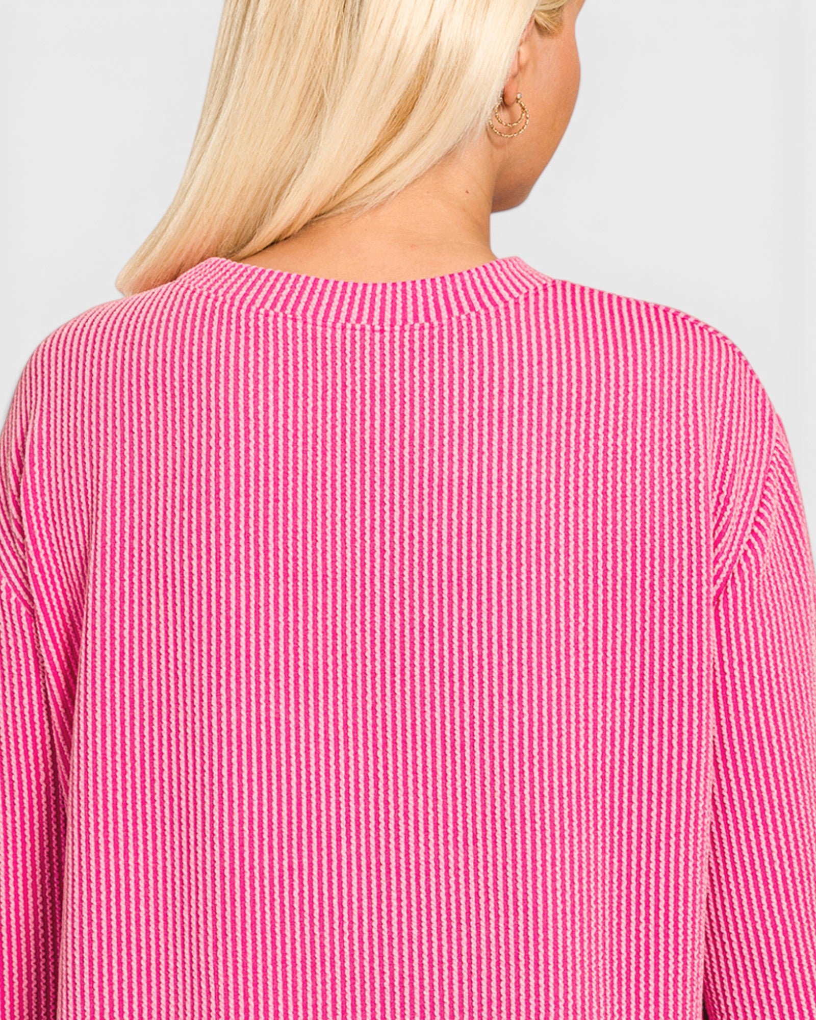 Close-up of a person wearing a pink and white striped sweater on a light gray background