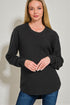 Woman wearing a black sweater against a plain background