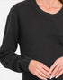 A close-up of a person wearing a dark charcoal gray textured knit sweater with a crew neck and ribbed cuffs, shown against a plain light background.